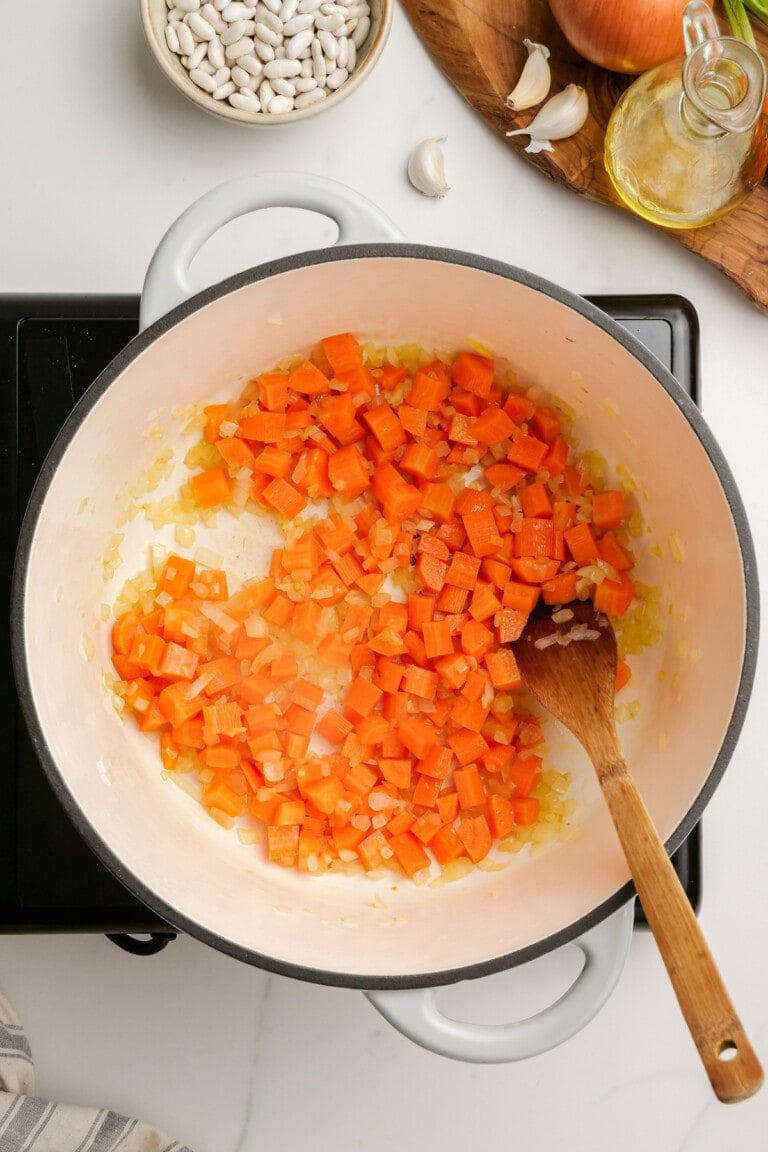 cooked carrots and onions in a pot with wooden spoon