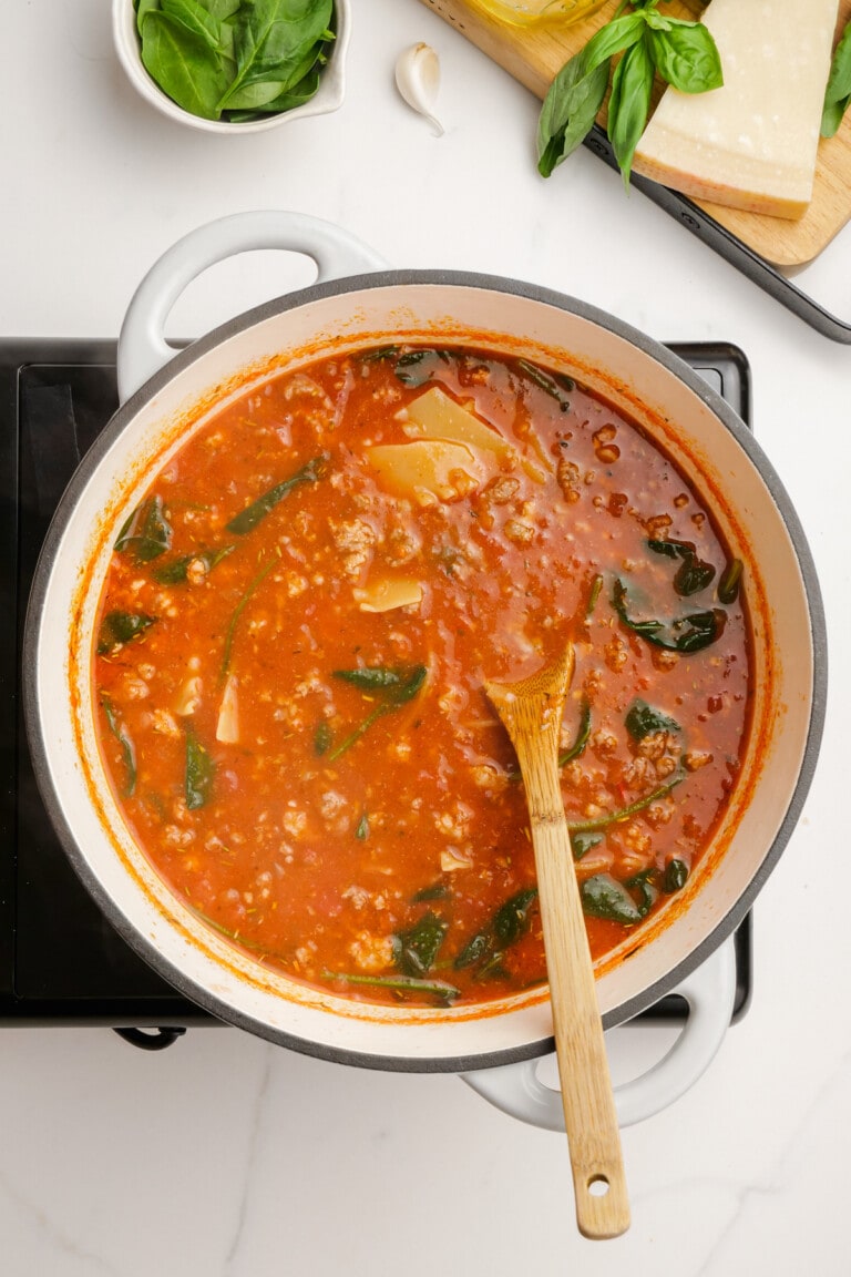 cooked lasagna soup ingredients in pot with wooden spoon