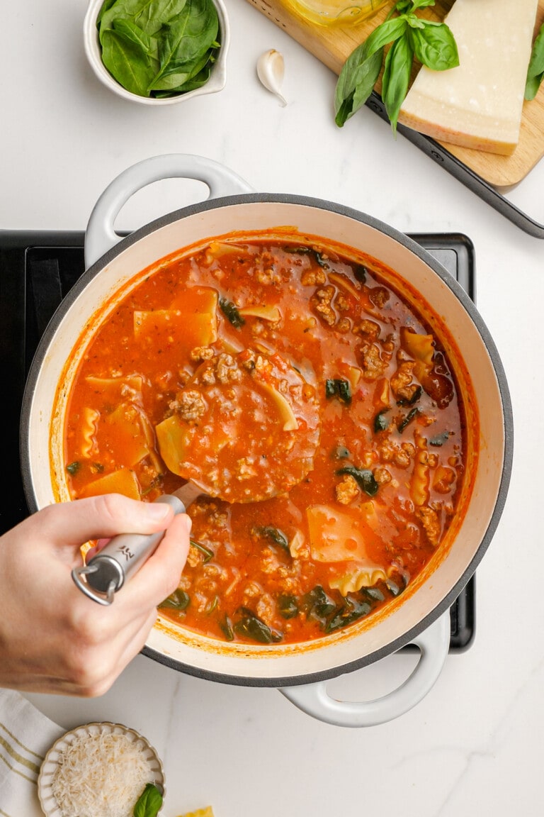 woman's hand ladling out cooked lasagna soup from pot