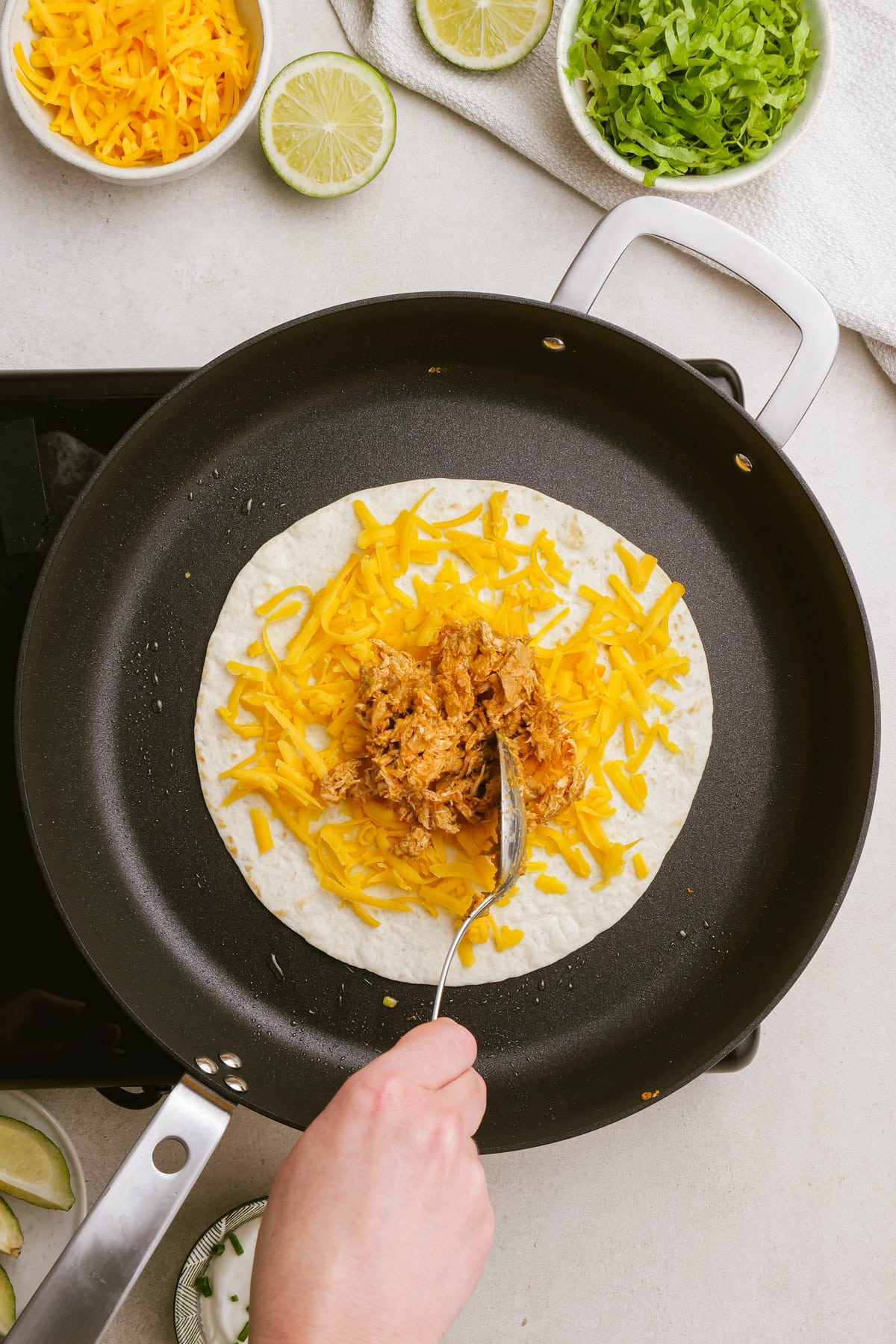 tortilla with shredded cheese and chicken on a skillet