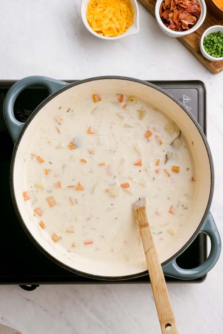 loaded-baked-potato-soup ingredients in pot with wooden spoon