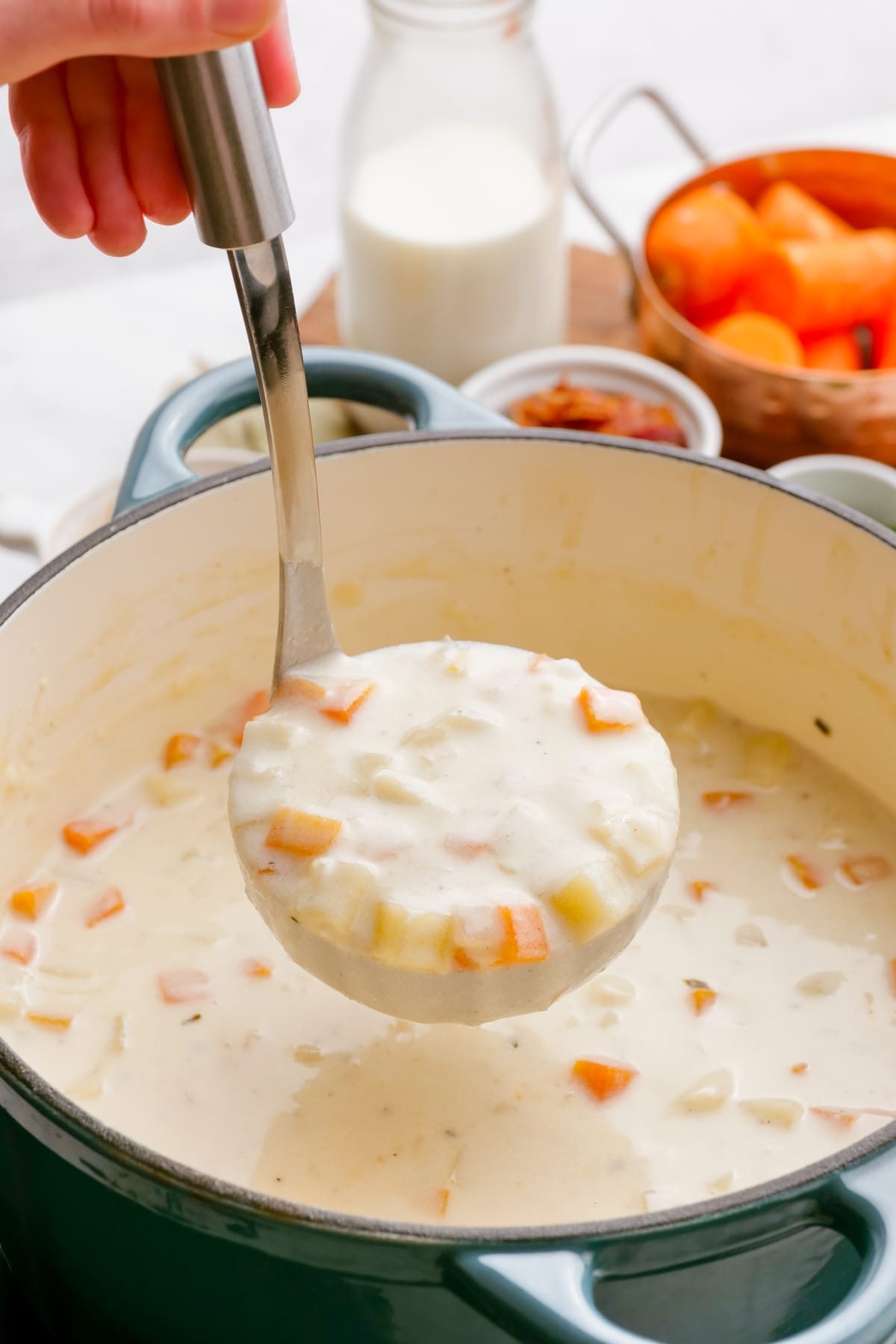 woman's hand ladeling out loaded-baked-potato-soup from pot