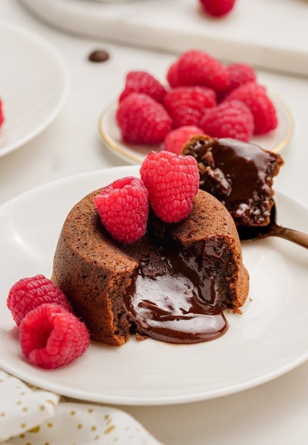 molten lava cake with raspberries on plates with spooned out filling