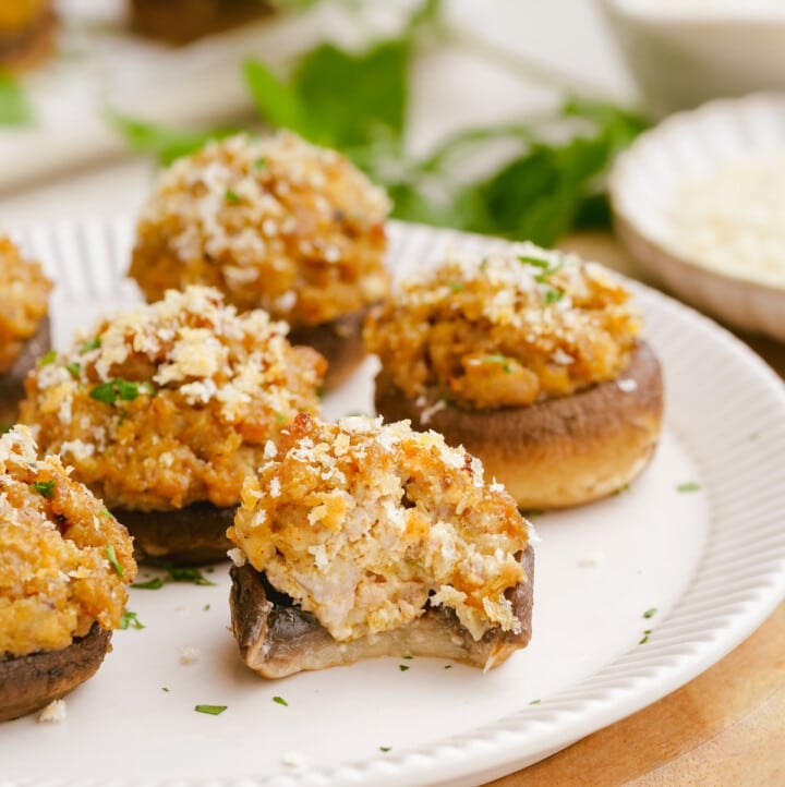 bite taken out of sausage-stuffed-mushrooms on plate