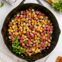 corned beef hash in a skillet with parsley garnish on the side