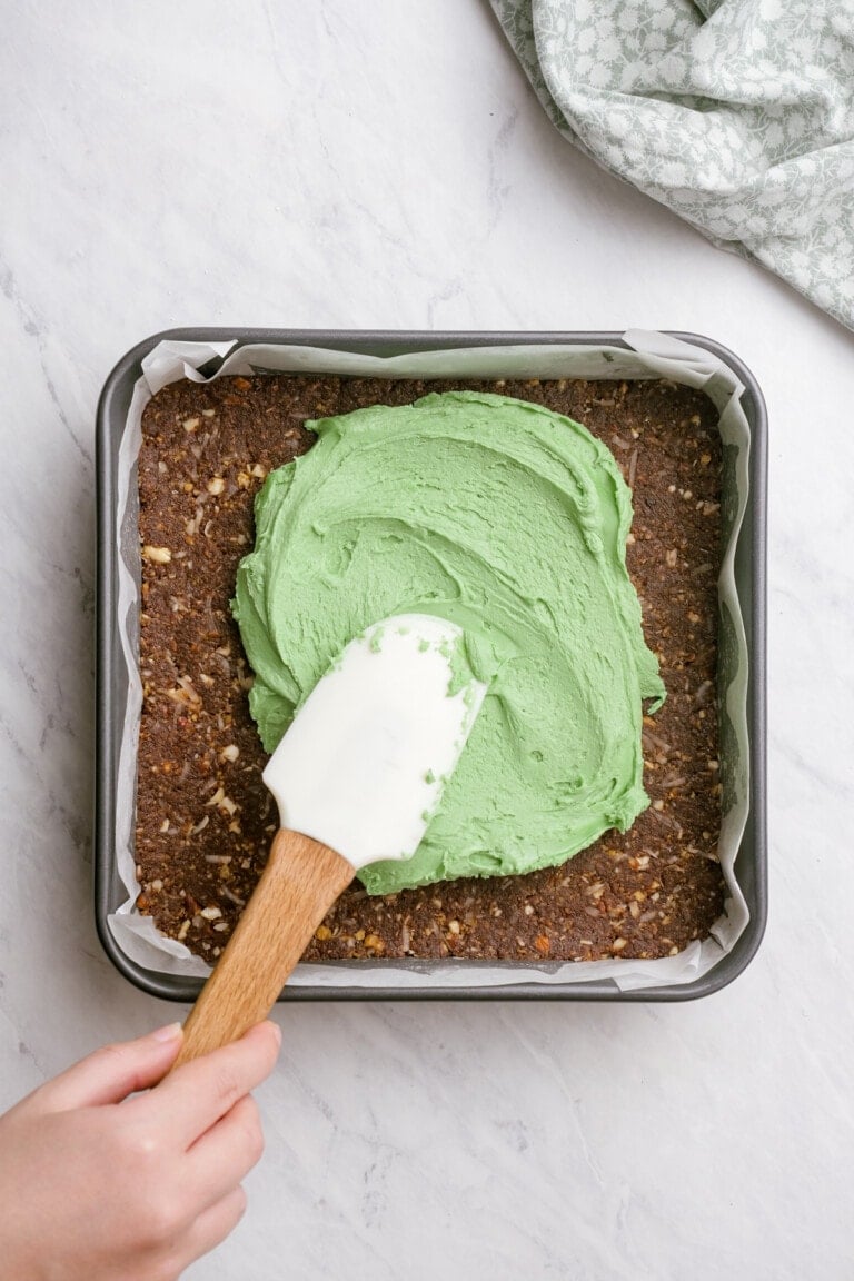 spreading green filling layer over bottom chocolate graham mixture