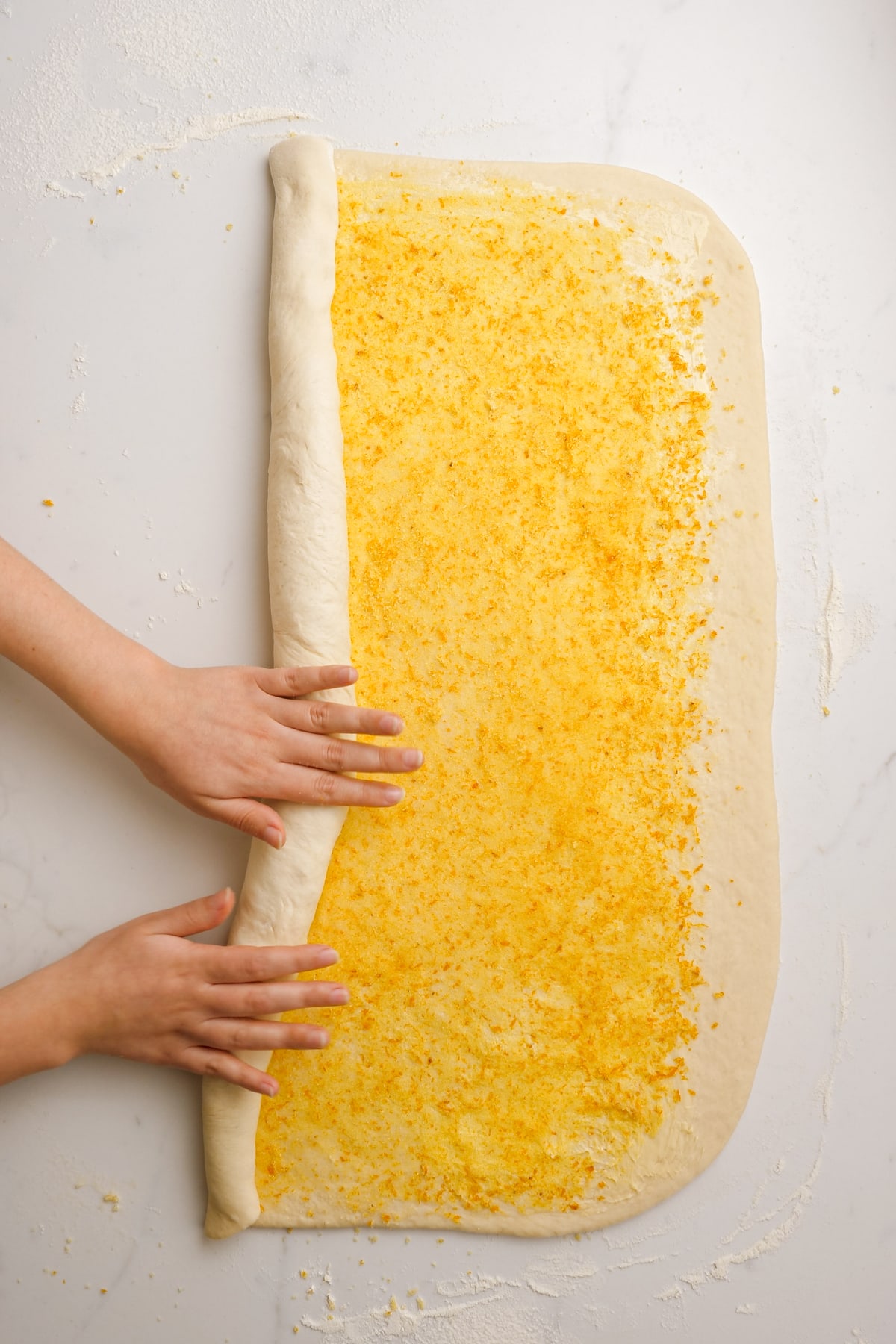 woman's hands rolling dough into a tight roll