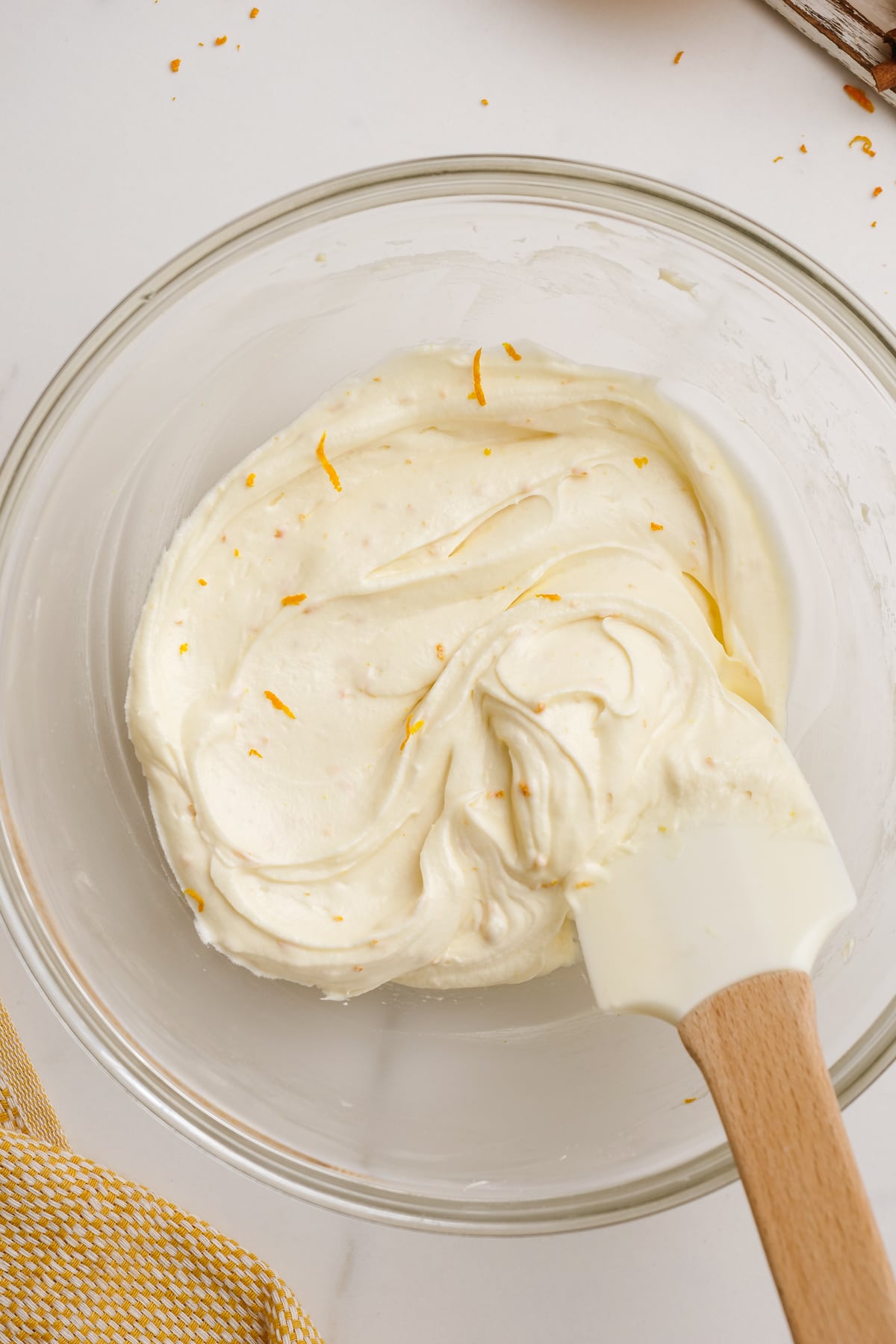orange frosting with rubber spatula in bowl