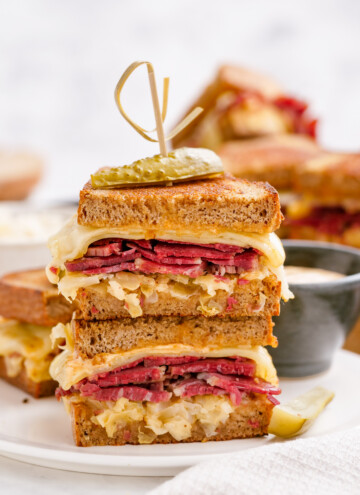 halves of reuben sandwich stacked with toothpick to secure