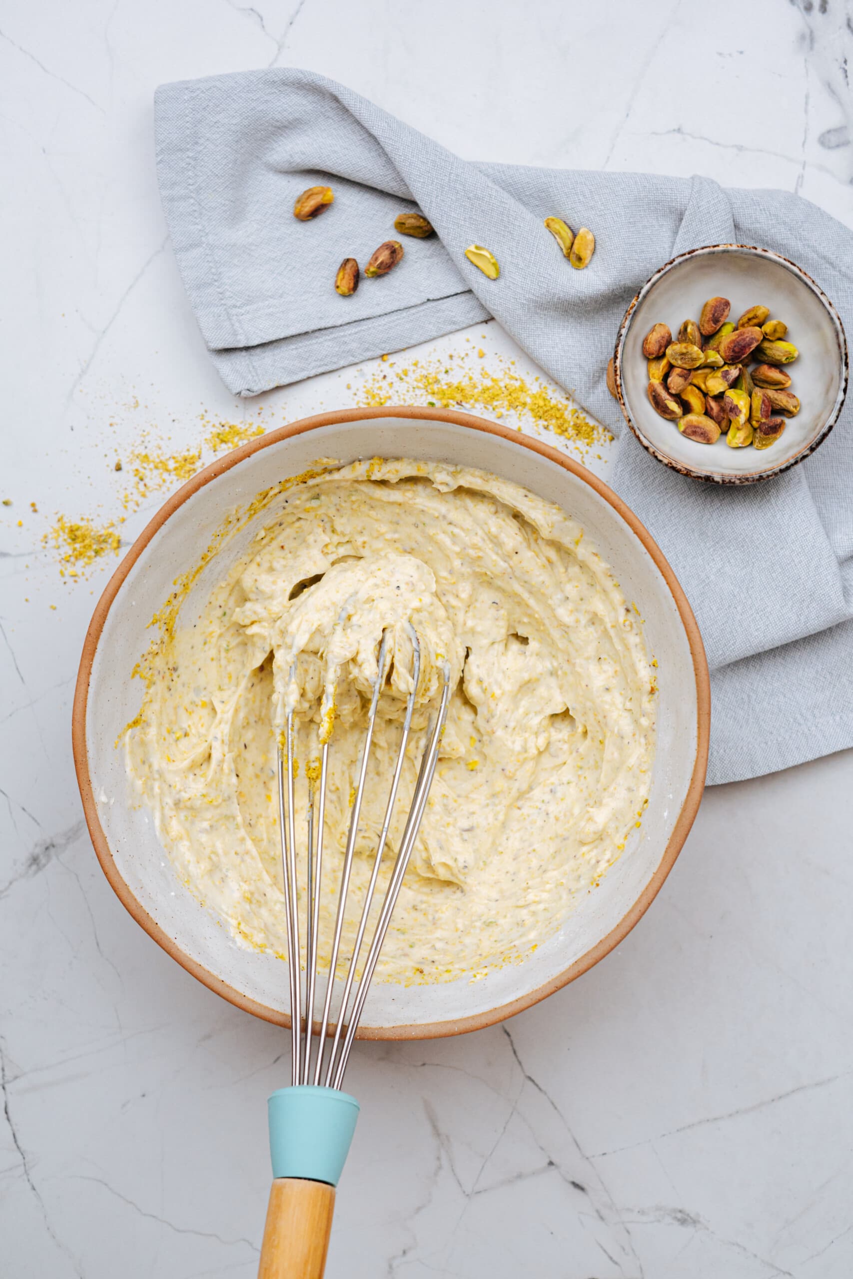pistachio lemon roll cake filling in a bowl with a whisk