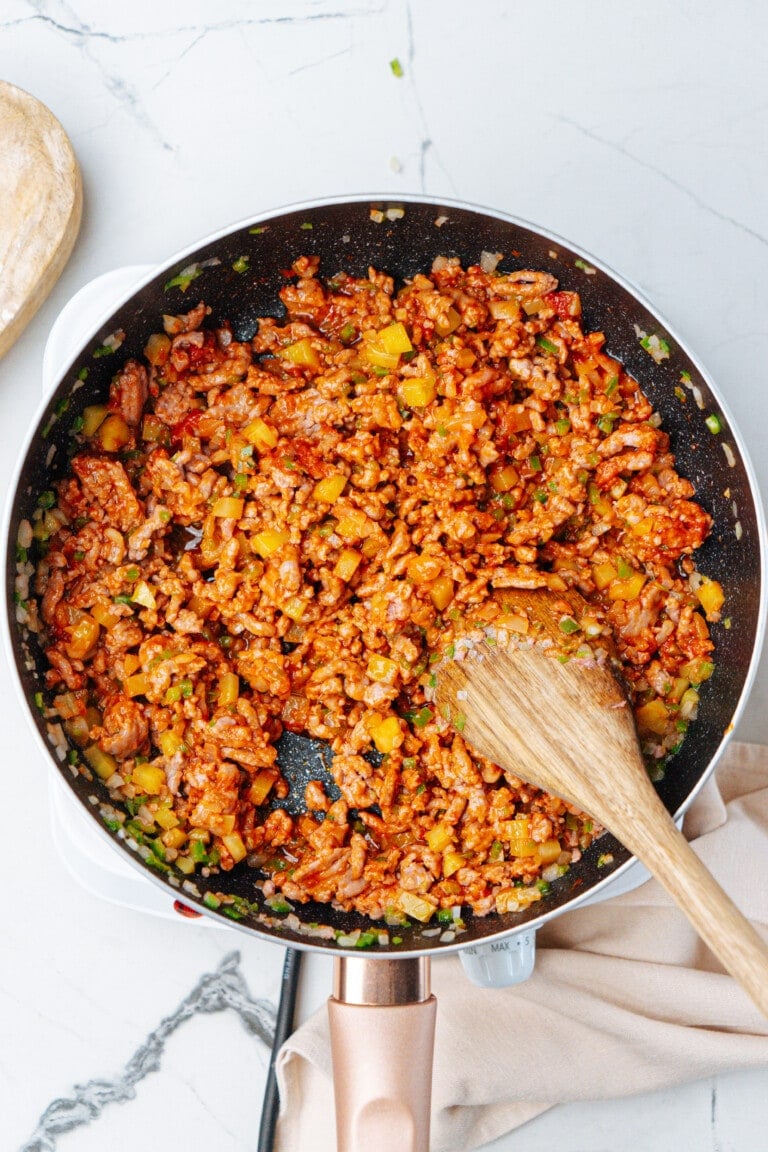 cooked taco meat ingredients in skillet with wooden spoon