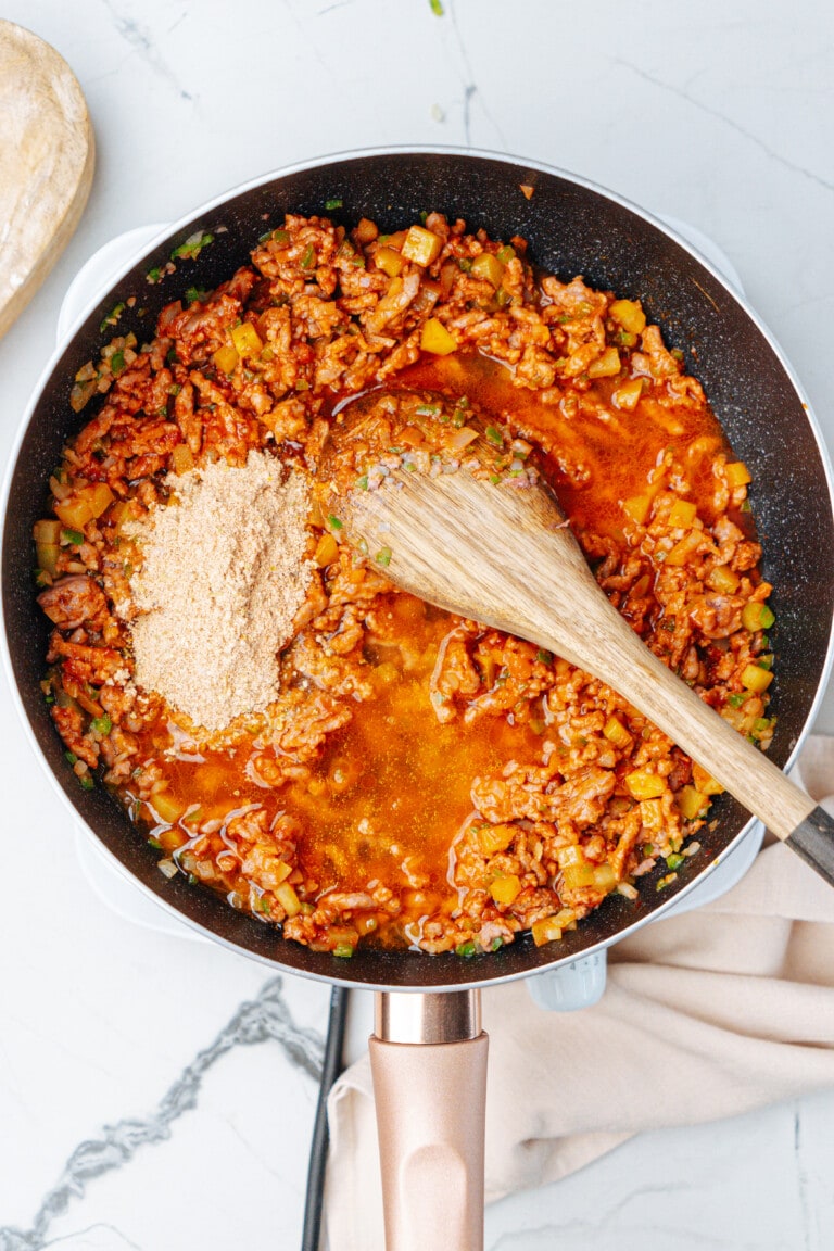 taco meat ingredients in skillet with wooden spoon