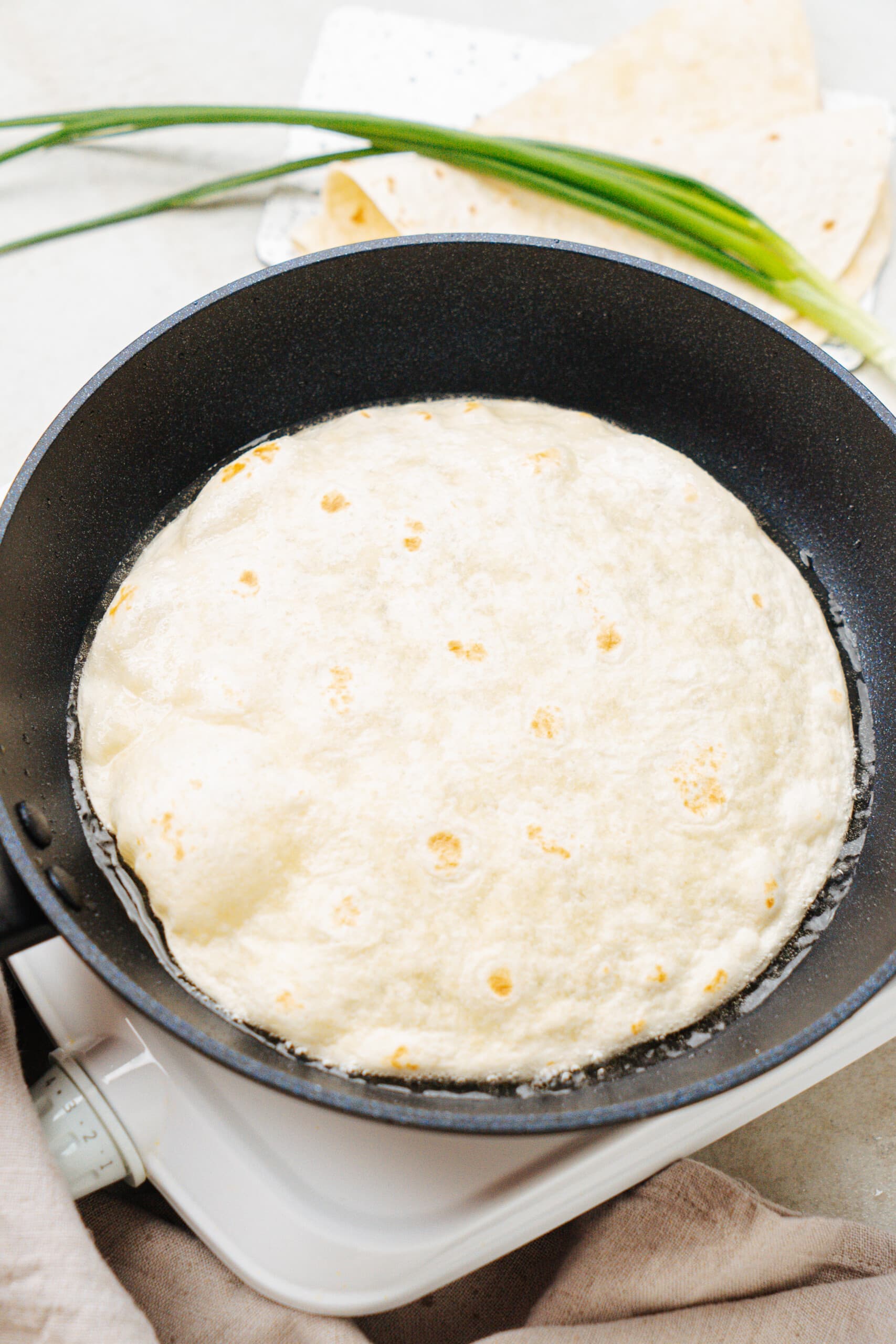 tortilla frying in a cast iron skillet
