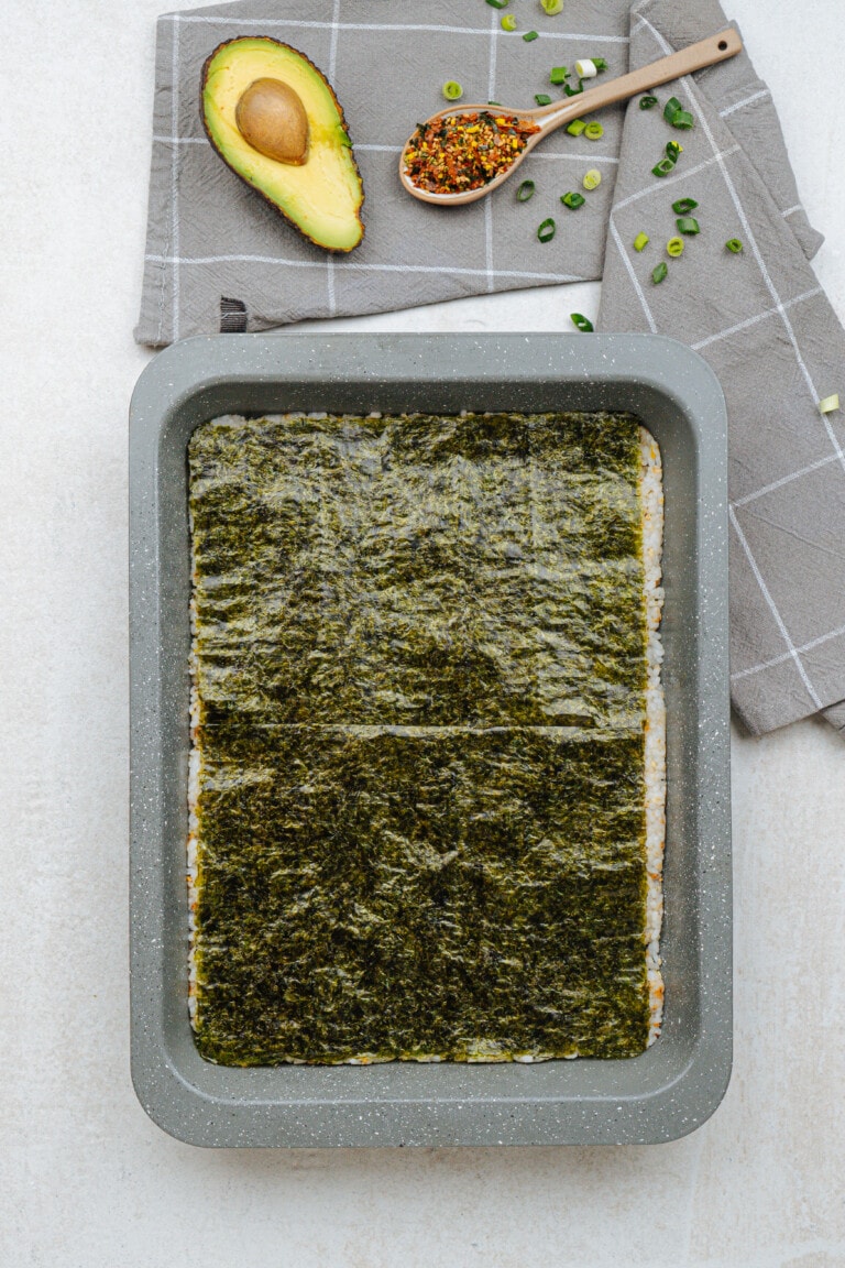 nori spread over the top of sushi rice in a pan