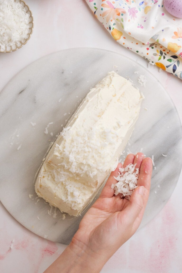 adding coconut to frosted bunny cake