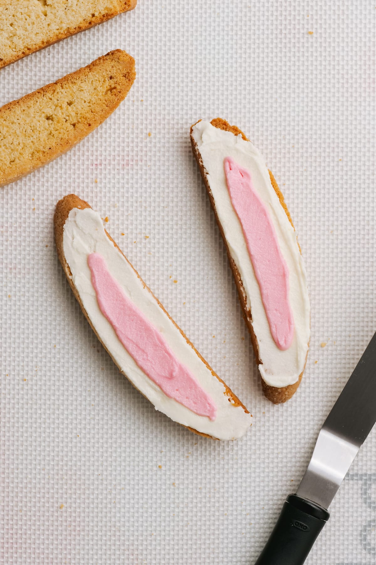 frosted biscotti with white frosting and pink frosting in the middle