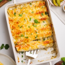 baking dish of chicken enchiladas with a serving spatula