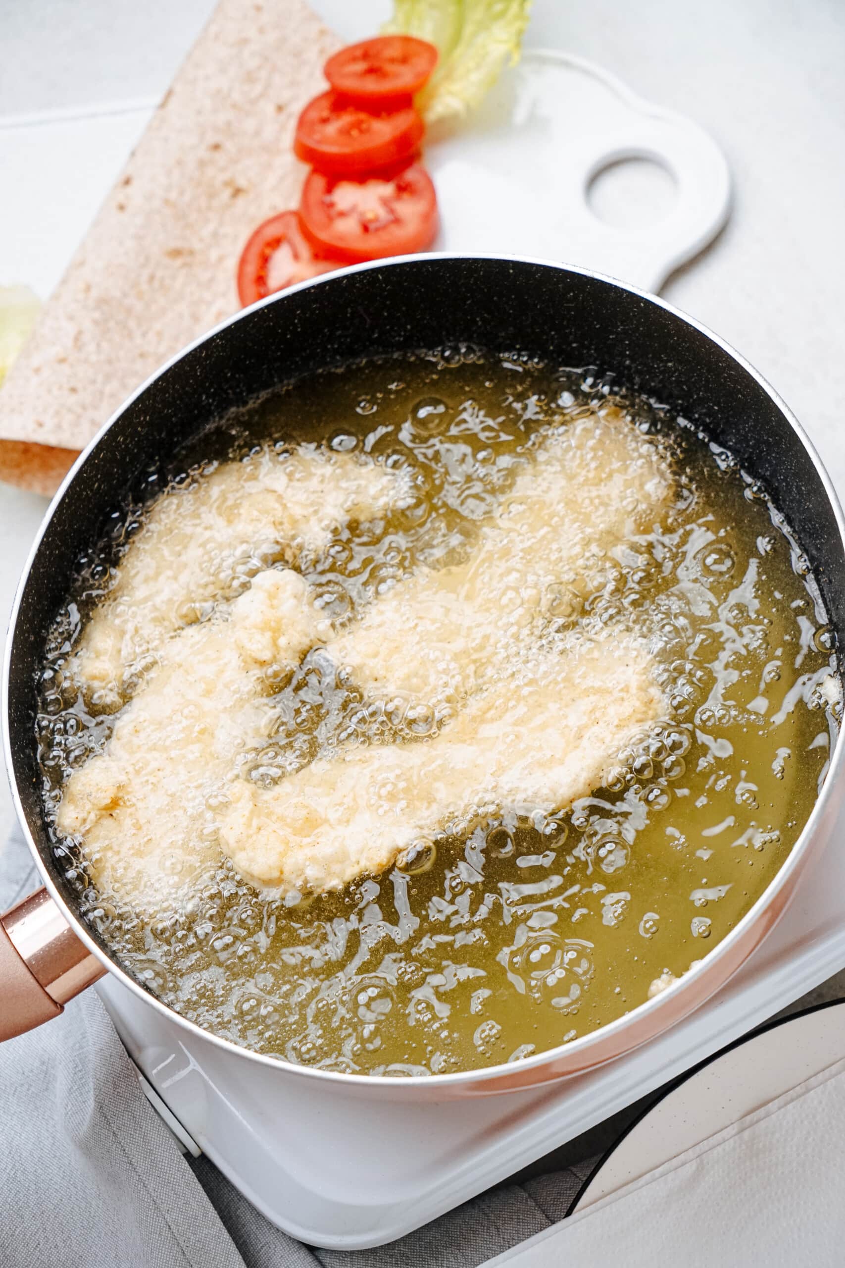 chicken frying in oil in a pan