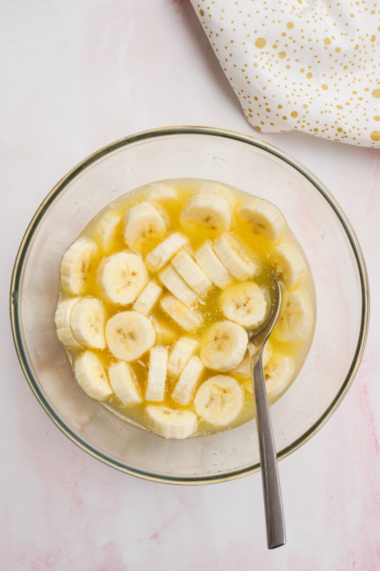 sliced bananas and pineapple juice in a glass bowl