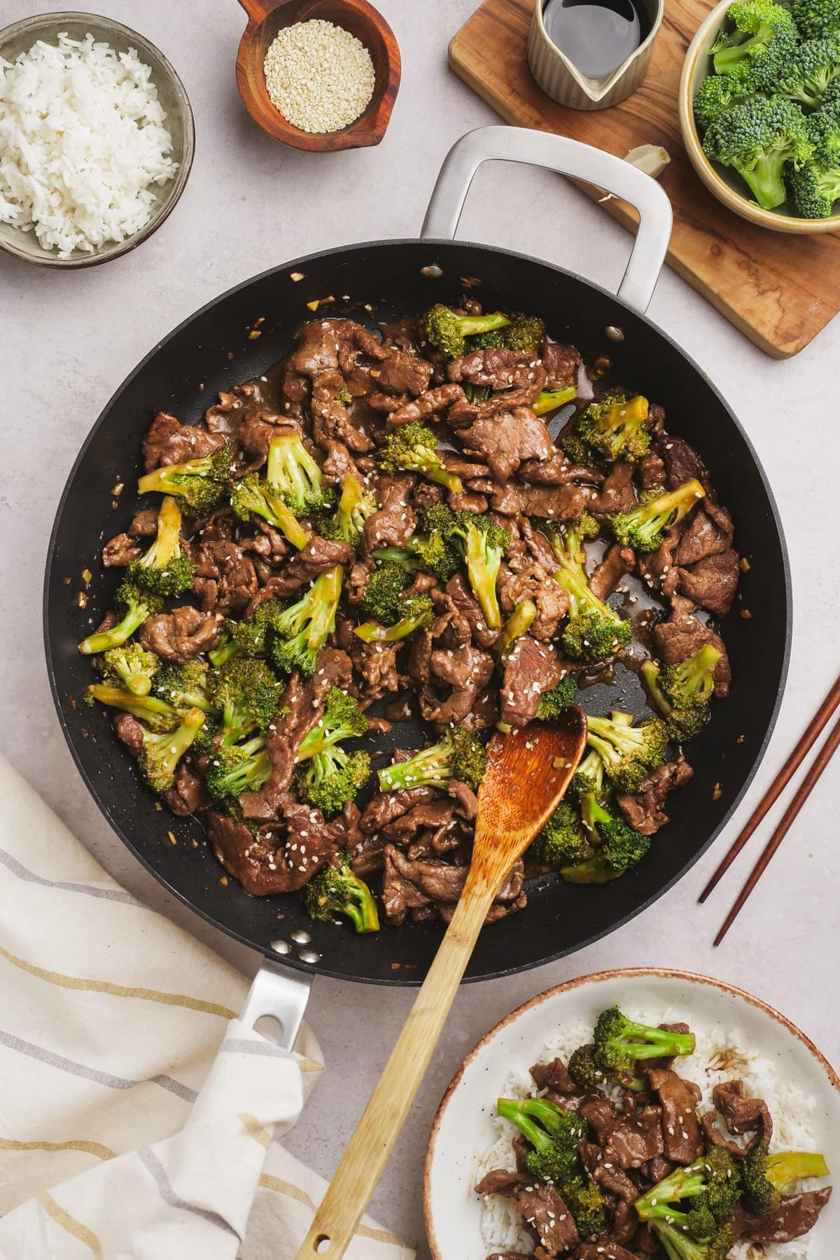 beef and broccoli in large skillet with wooden spoon