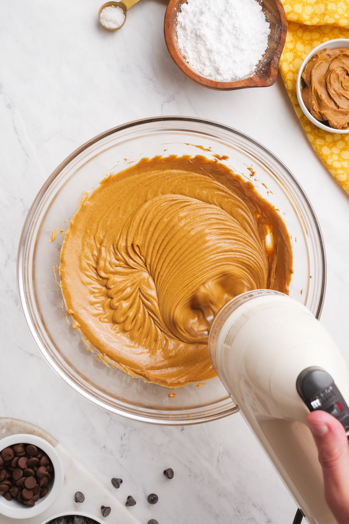 hand mixer blending peanut butter and butter together in a glass bowl