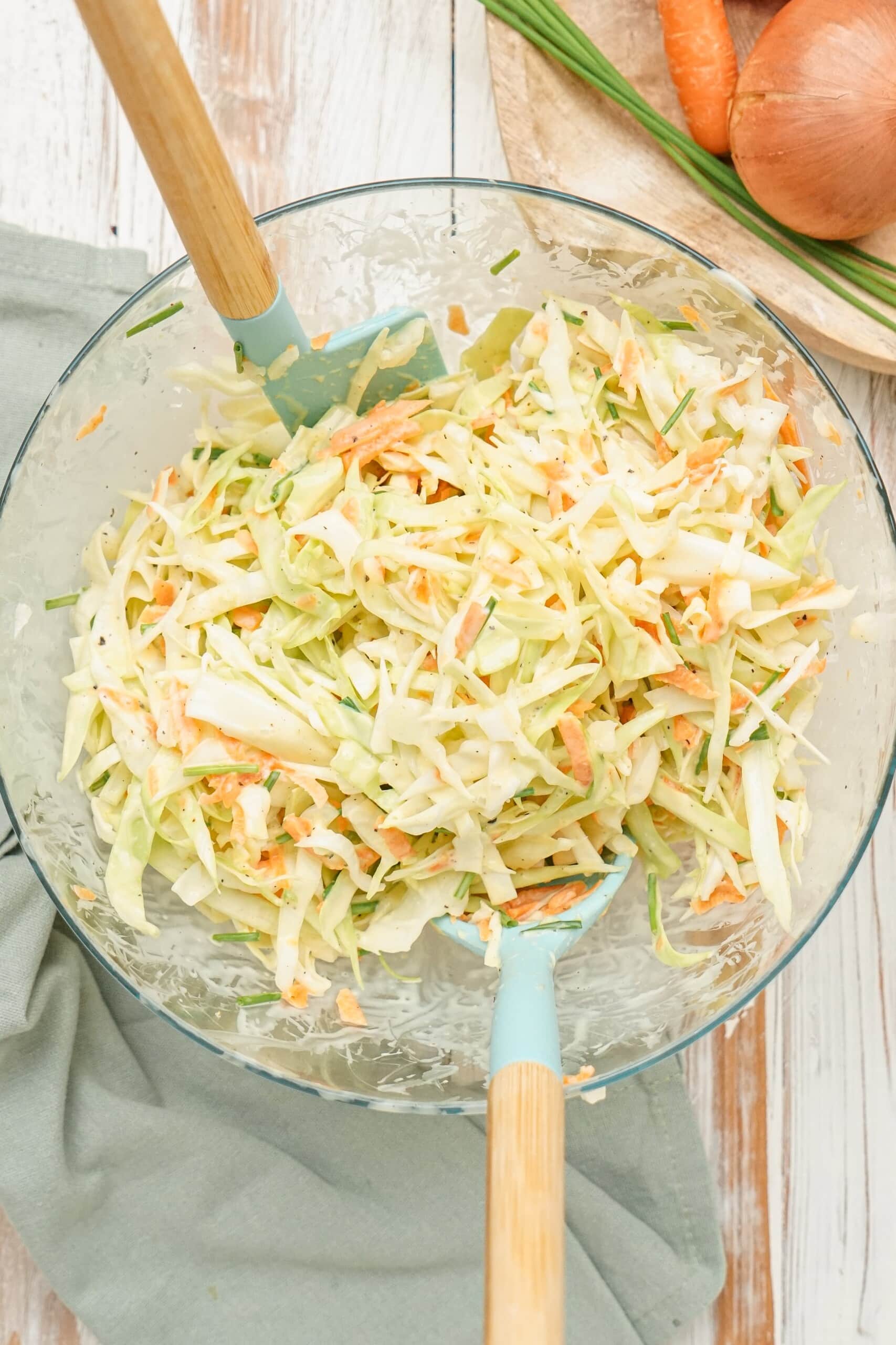 tossing together slaw sauce and coleslaw