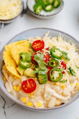 A bowl of white bean and chicken soup with tortilla chips.