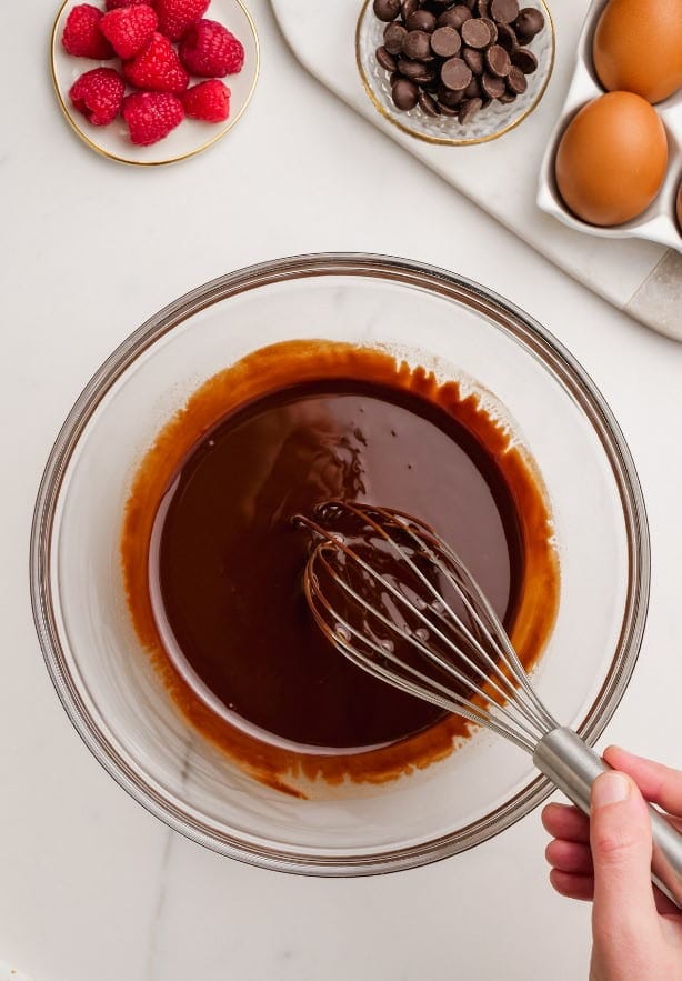 butter and chocolate melted in bowl with woman's hand whisking