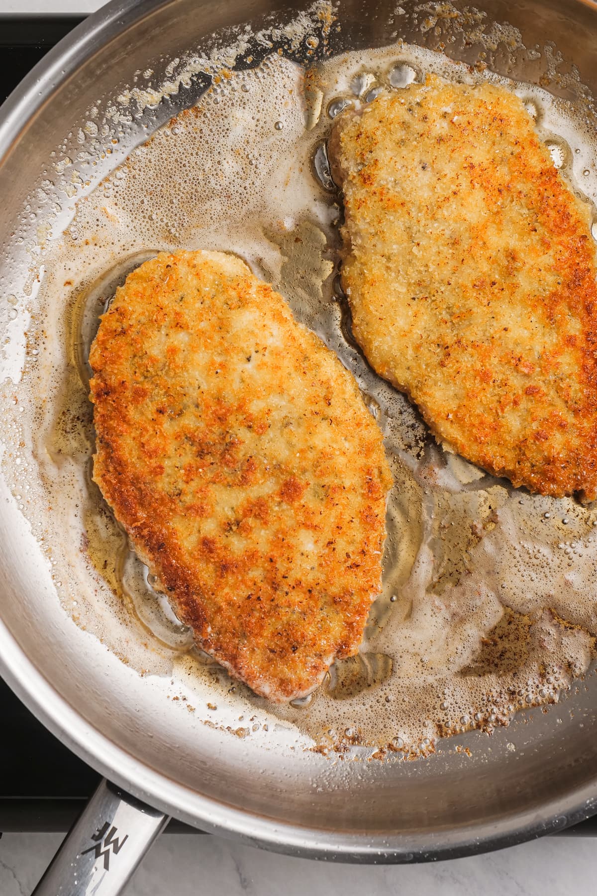 chicken parmesan frying in a hot skillet