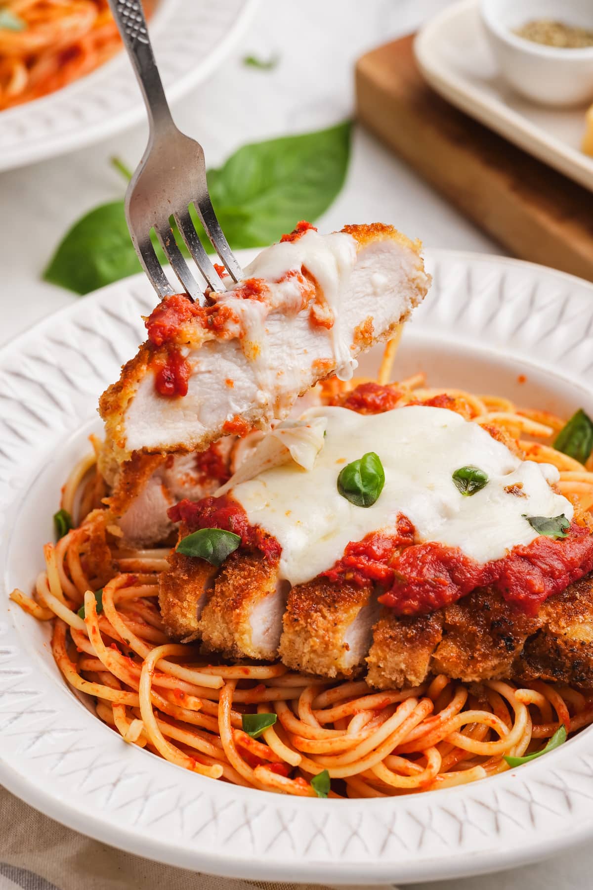 chicken parmesan in a bowl with a piece of chicken on a fork