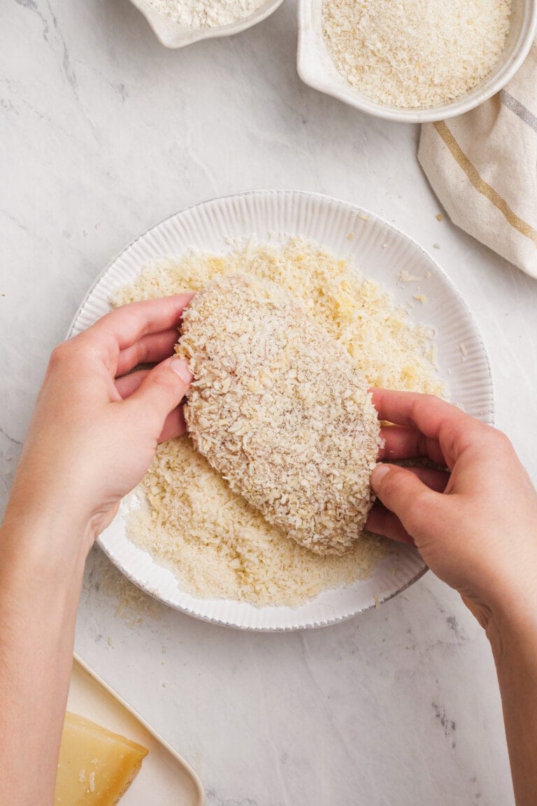 dredging chicken breast in parmesan cheese and panko bread crumbs