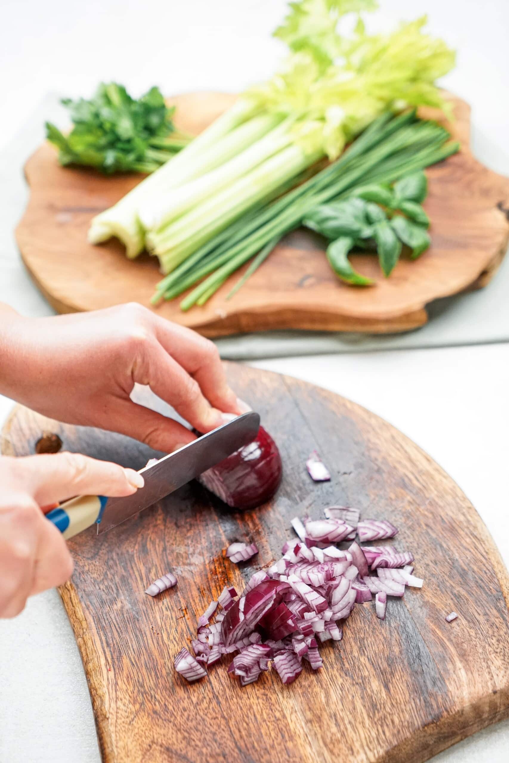 A woman's hands are chopping red onions on a cutting board