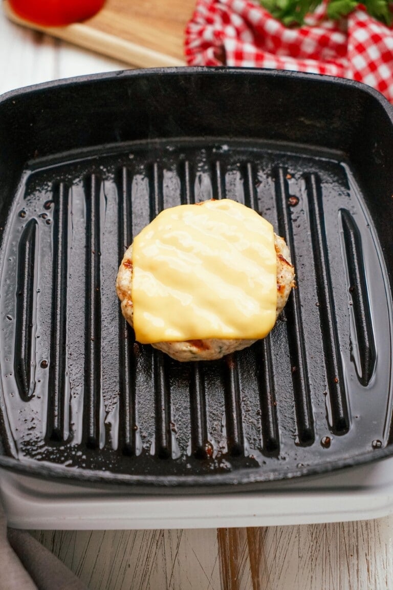 melted cheese on top of turkey burger on the grill