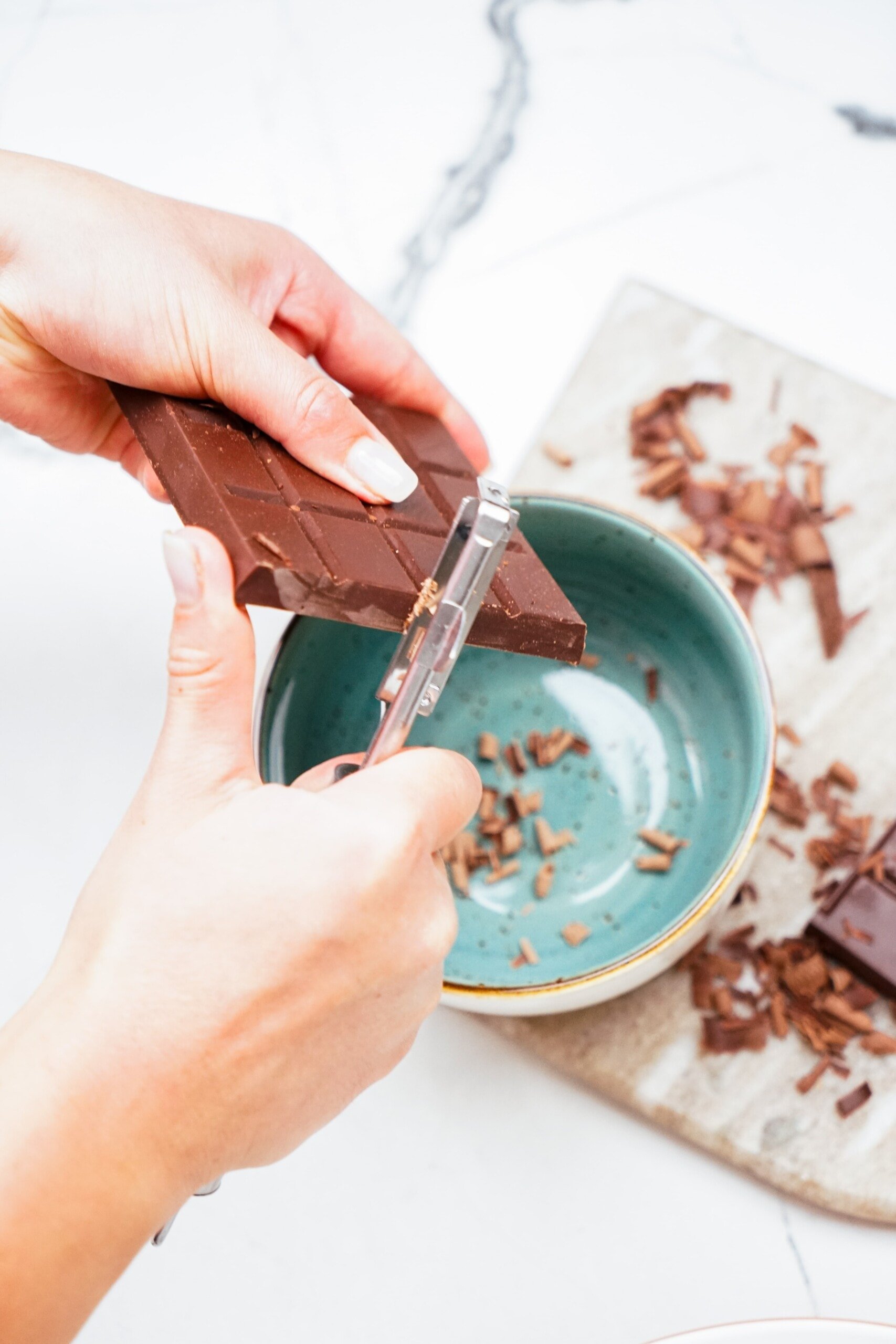 woman's hand using a veggie peeler to shave off a chocolate bar