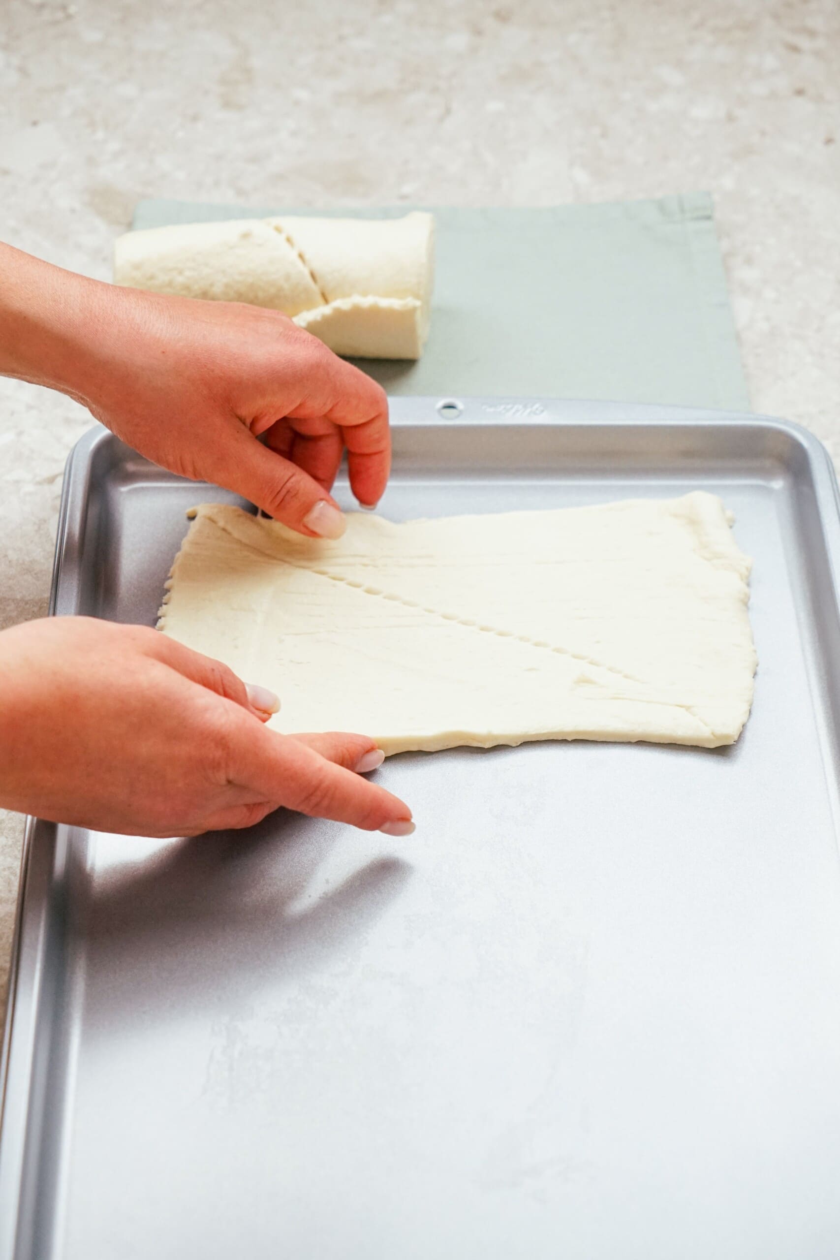 woman's hands laying crescent dough out on a baking sheet