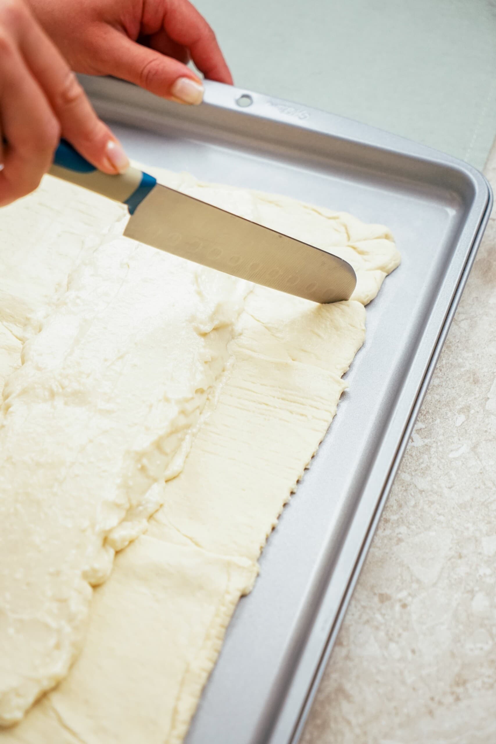 knife cutting diagonal cuts into the crescent dough