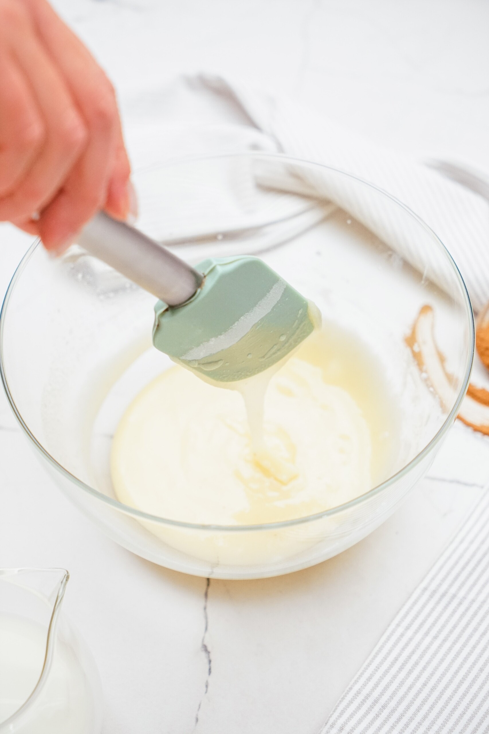 brown butter frosting in a bowl with rubber spatula