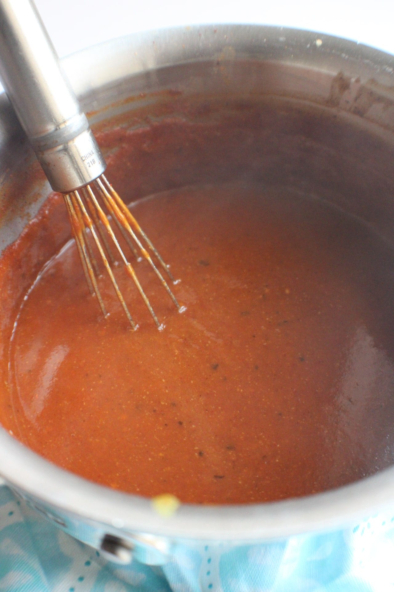 enchilada sauce simmering in a pot with whisk