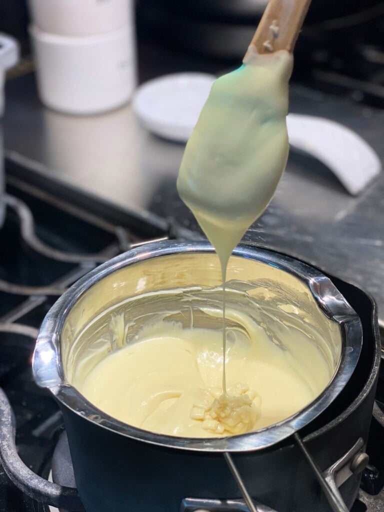 melted white chocolate in a saucepan with a spoon