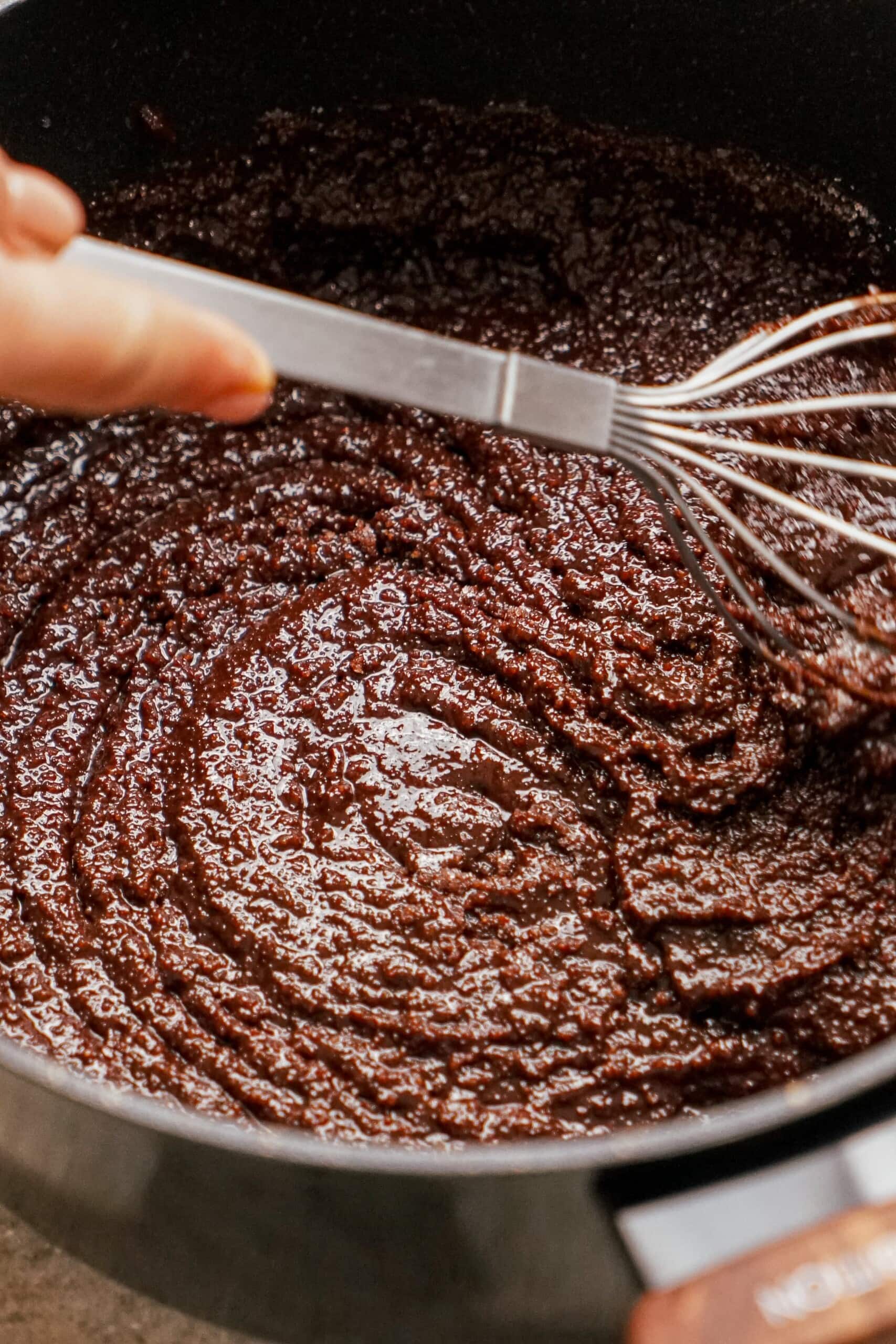 woman's hand whisking sugar into chocolate mixture