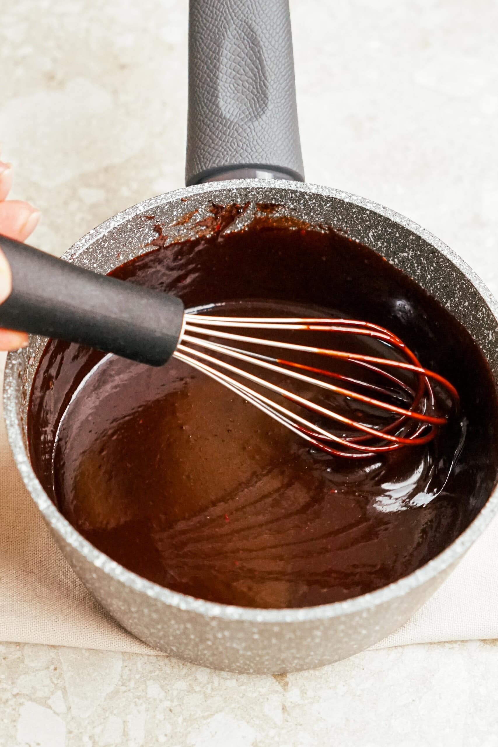 stirring hot fudge with a whisk