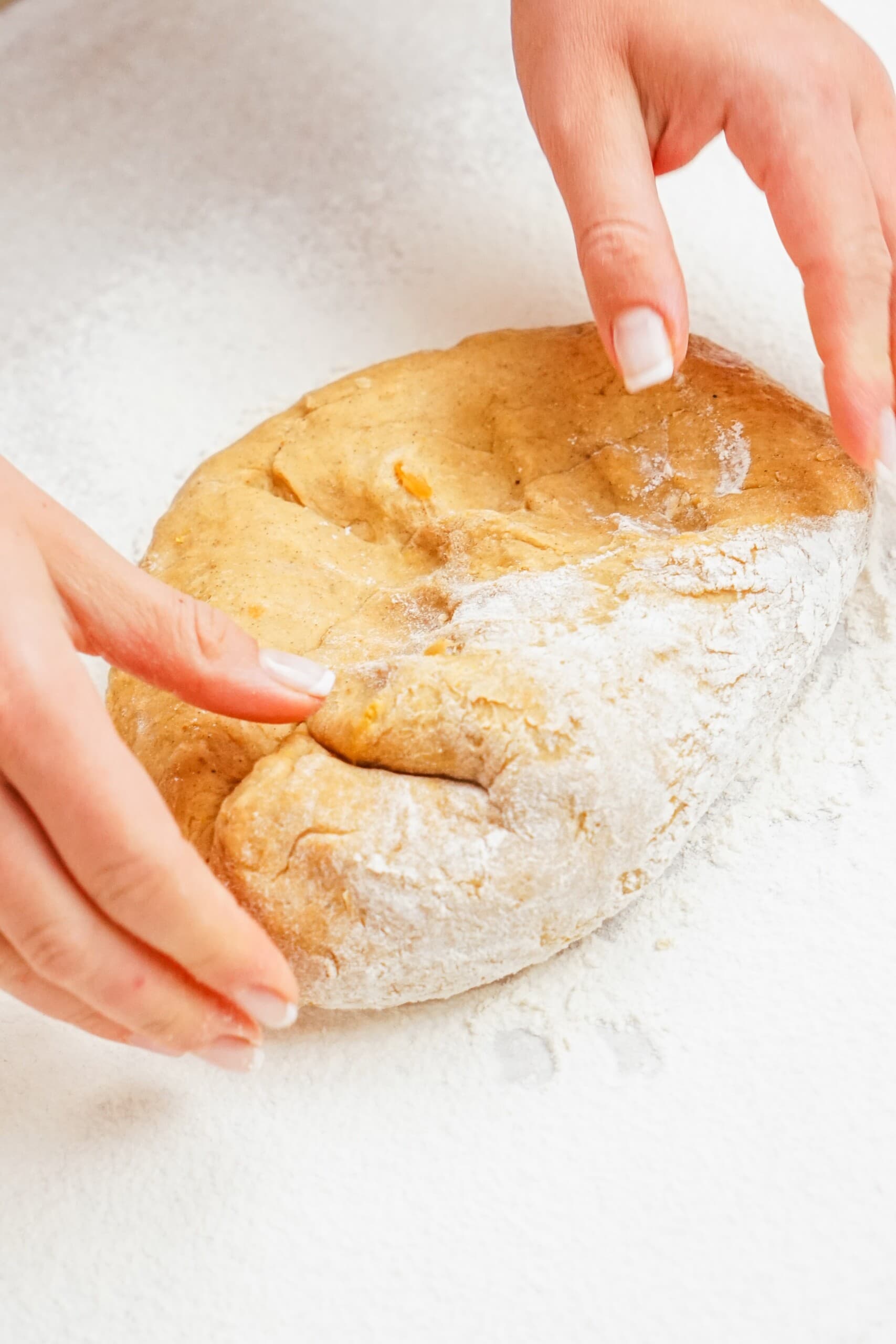 woman's hands covering donut dough in flour to roll out