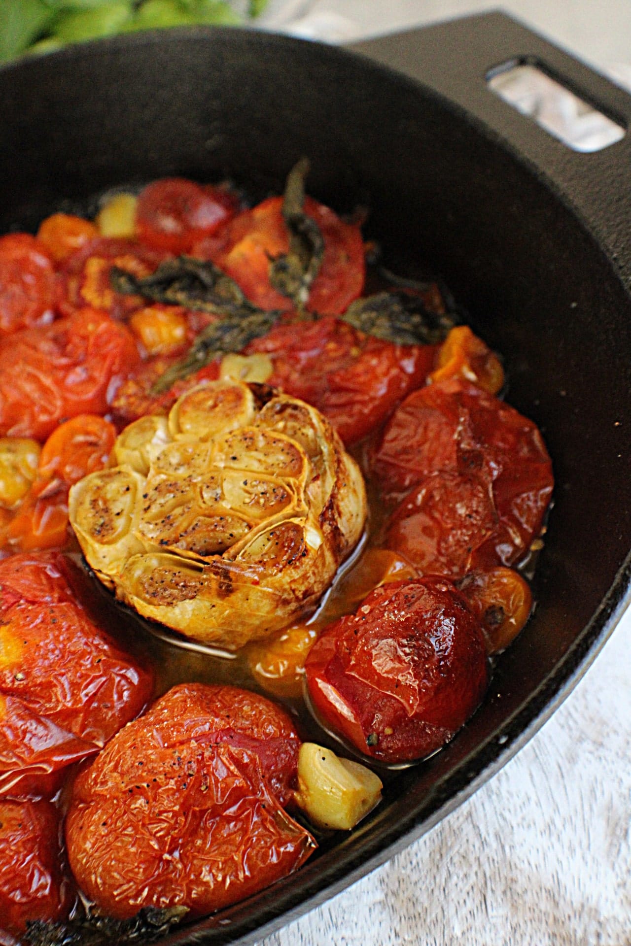 roasted garlic bulb in a skillet with roasted tomatoes