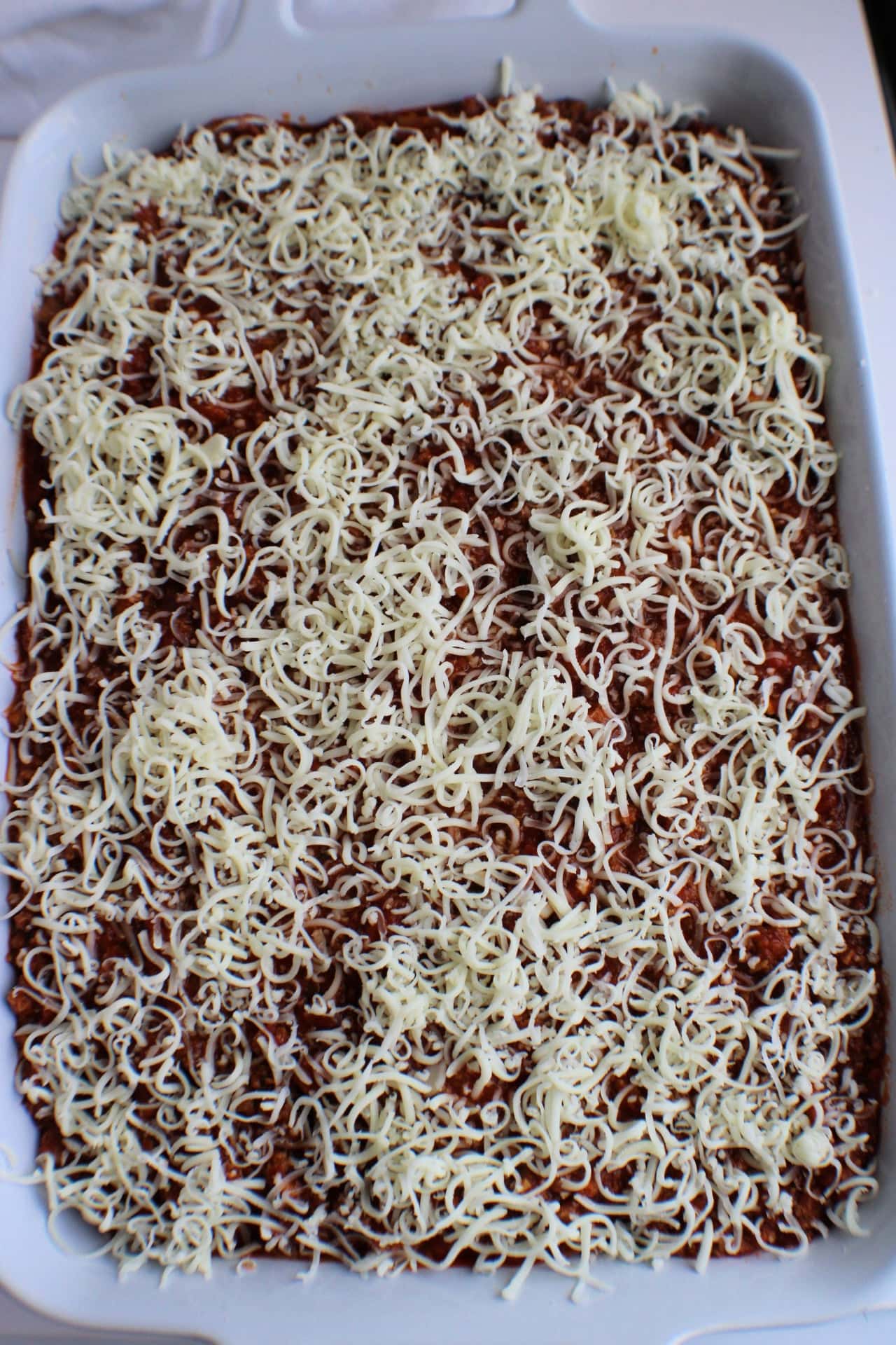 baked spaghetti casserole with shredded cheese over the top