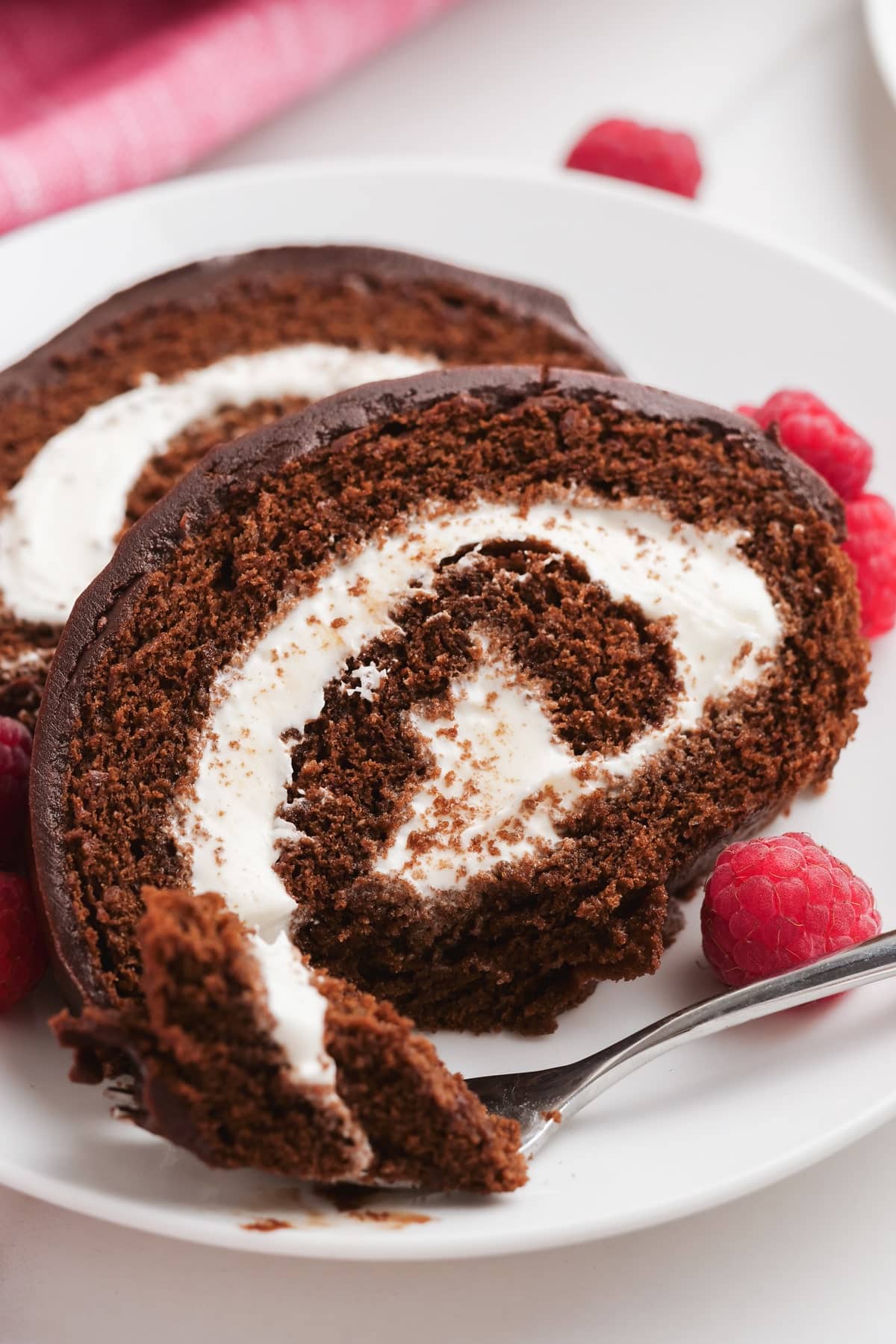chocolate swiss roll slices on a plate with a fork