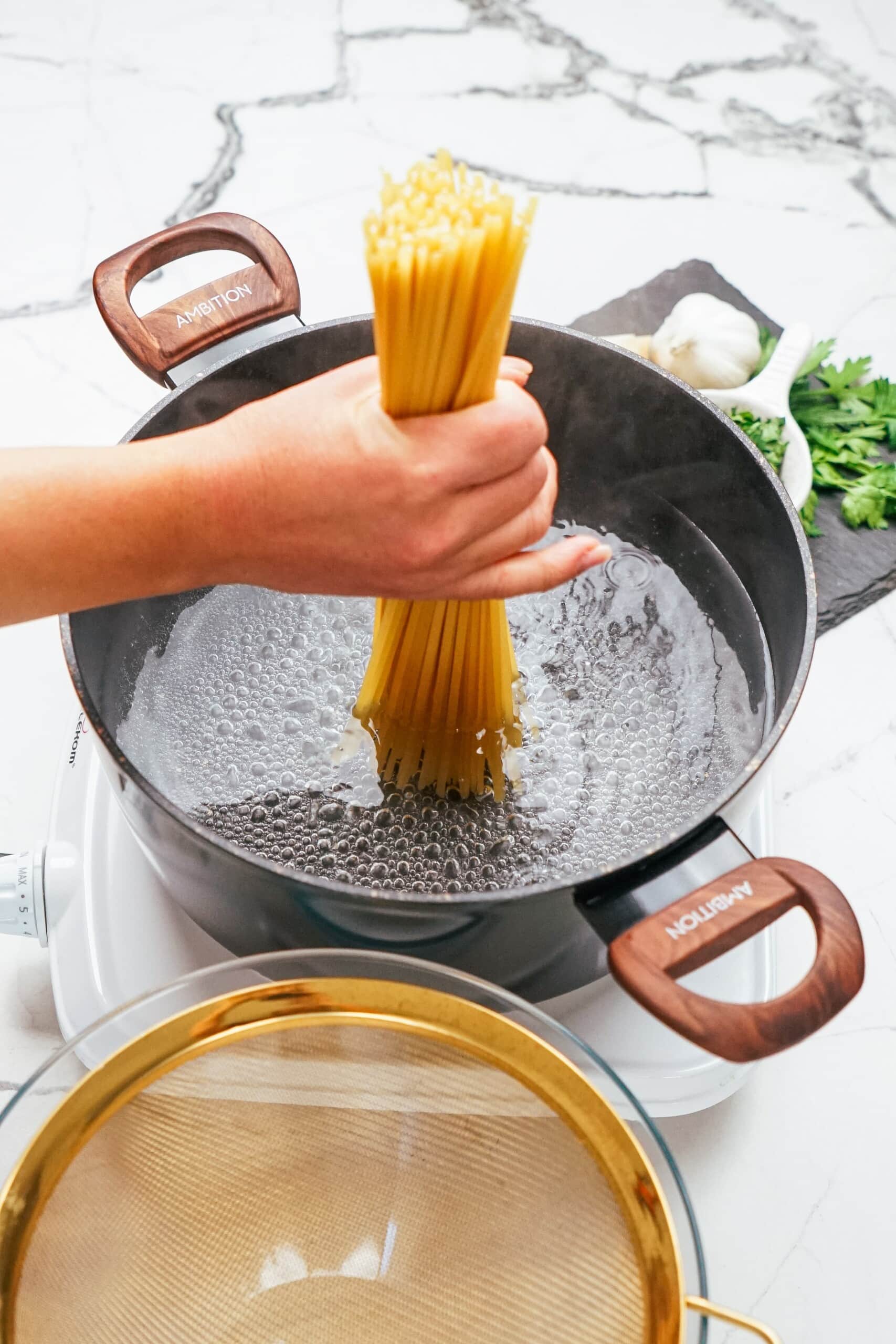 woman adding linguine to a large pot of boiling water