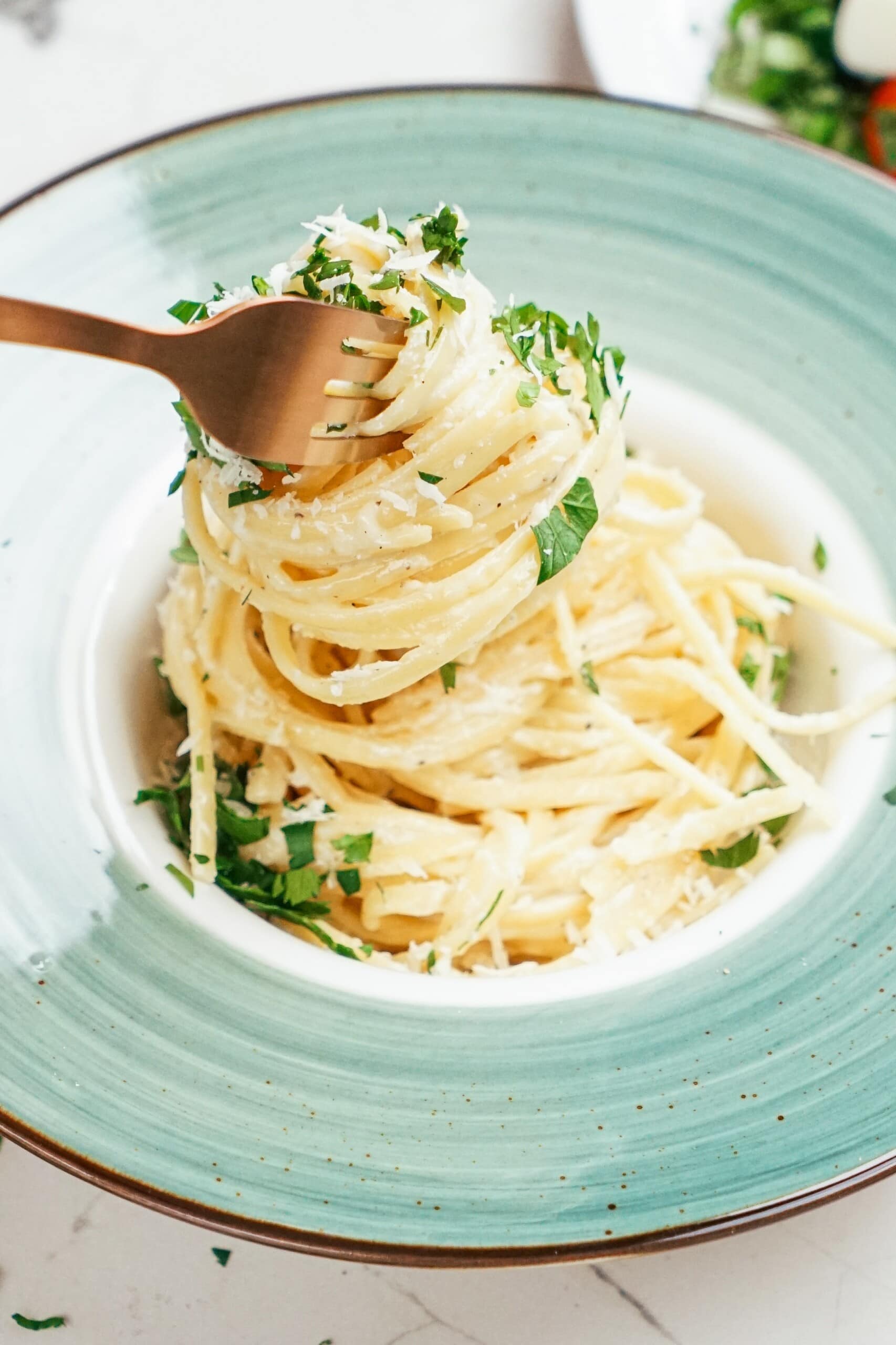 parmesan linguine in a pasta bowl twirled on a gold fork