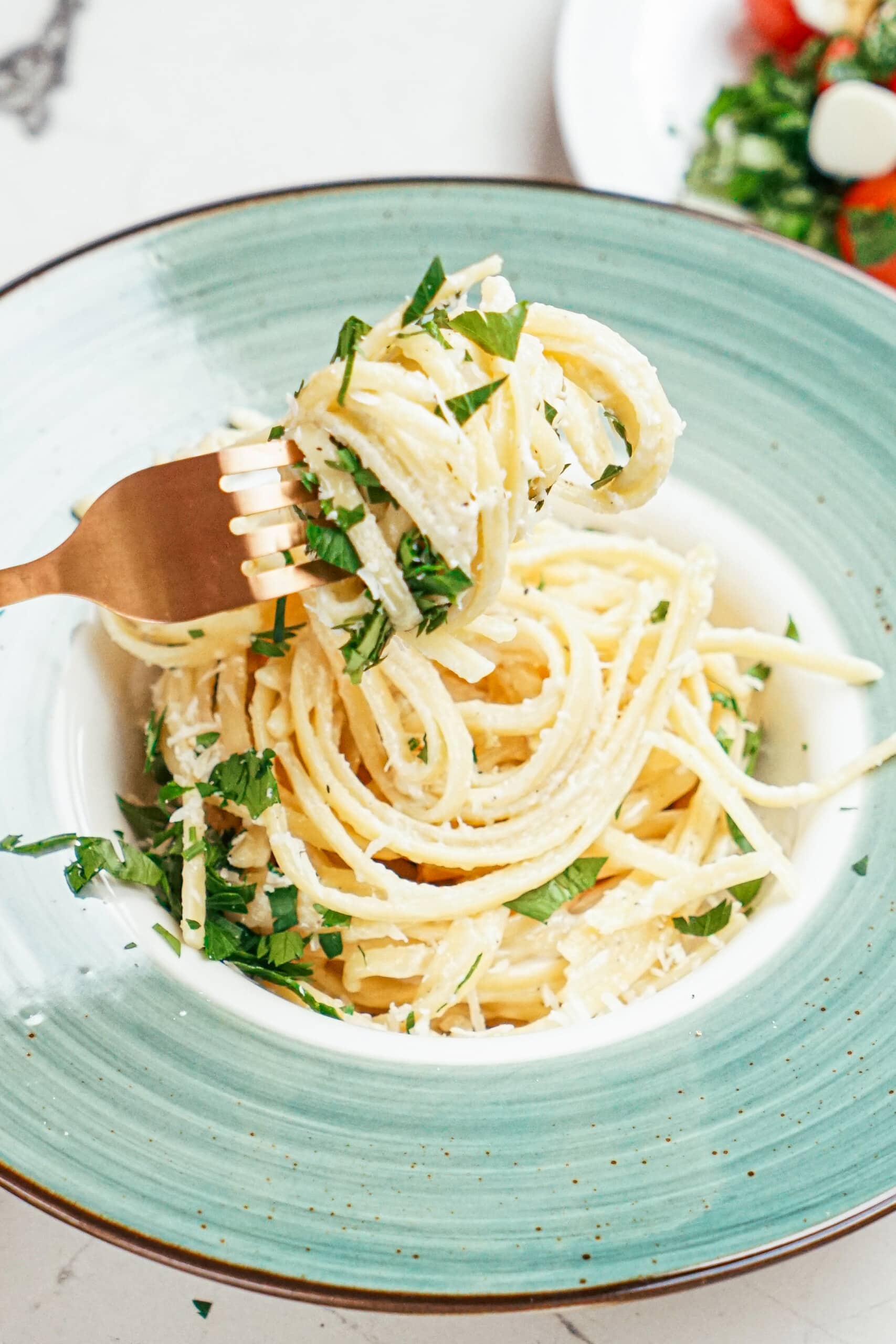 gold fork twirling Parmesan Garlic Linguine Pasta in green bowl