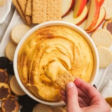 pumpkin dip and a woman's hand dipping cookie into the dip