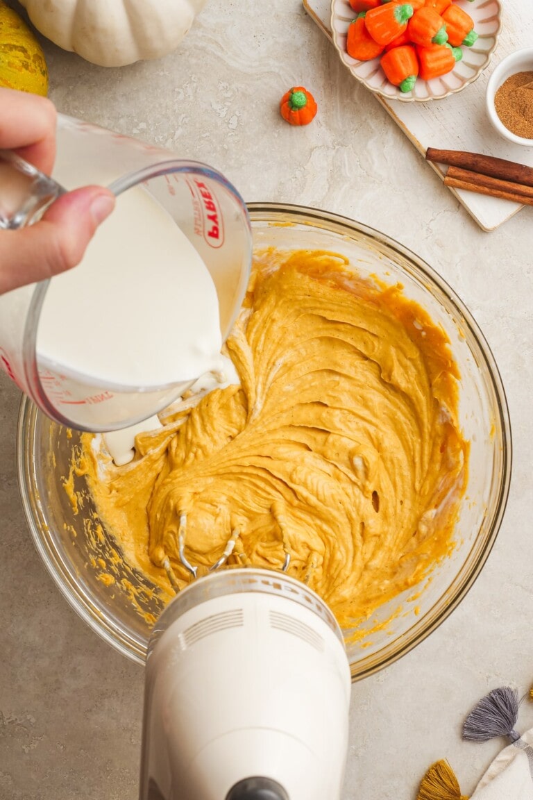 woman's hand pouring in heavy cream to the dip mixture
